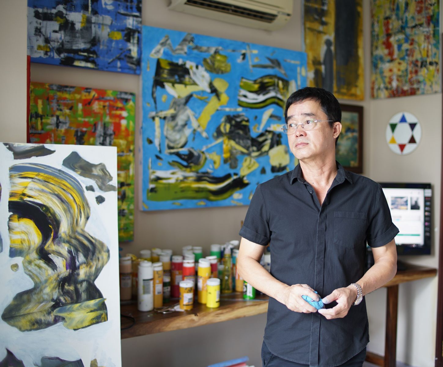 Artist Dinh Phong at his workshop and his paintings - Photo: Pham Tuan Ngoc.